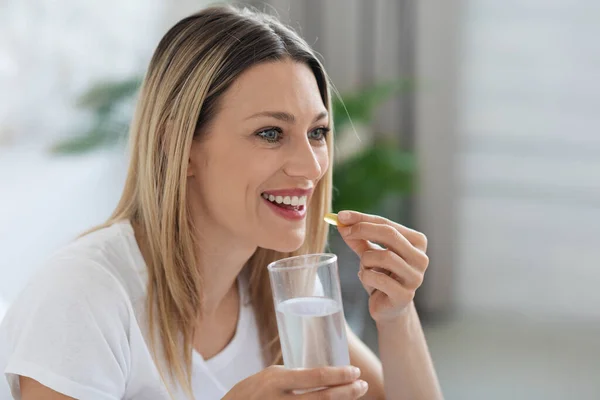 Attractive Blonde Millennial Woman Taking Medicine Yellow Gelatin Capsule Looking — Stock Photo, Image