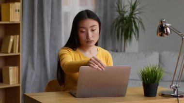 Domestic workplace. Zoom out portrait of young asian woman freelancer opening laptop and start working at home office, slow motion