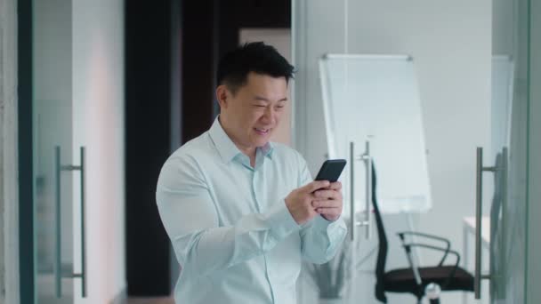 Позитивный Азиатский Бизнесмен Средних Лет Печатающий Смартфоне Общающийся Коллегами Улыбающийся — стоковое видео
