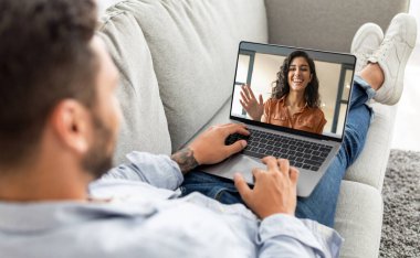 Dizüstü bilgisayarı olan bir adam, evinde kanepede dinlenirken kız arkadaşıyla sohbet ediyor, genç bir adam, gülümseyen genç bir kadınla bilgisayardan video görüşmesi yapıyor, uzaktan iletişimin keyfini çıkarıyor, Kolaj yapıyor.