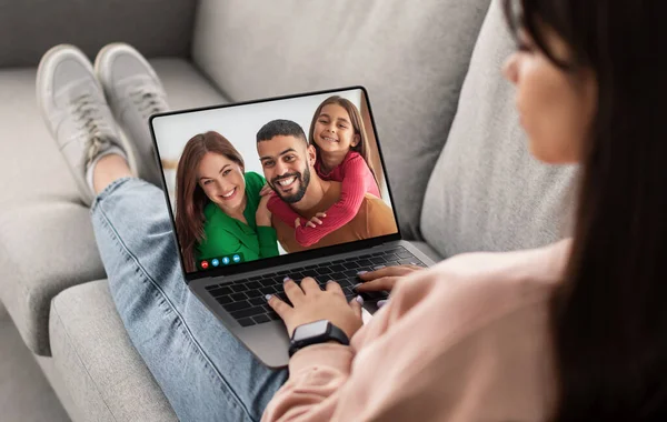 Remote Communication. Young Woman Making Teleconference With Friends On Laptop Computer While Relaxing On Couch At Home, Millennial Female Having Online Chat With Arab Family Of Three, Collage