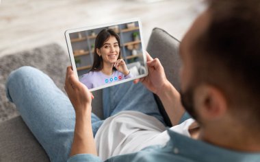 Genç adam, kız arkadaşıyla görüntülü sohbet için dijital tablet kullanıyor. Milenyum çifti internet üzerinden konuşuyor. Sanal iletişimden, yaratıcı kolajdan keyif alıyor.