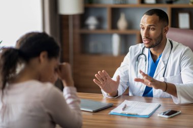 Orta Doğulu genç bir doktor hasta Afrikalı Amerikalı kadın hasta, terapist, üzgün müşteriyi teselli eden, motive eden, tavsiye veren, klinik içini rahatlatan biriyle konuşuyor. Kanser, onkoloji.