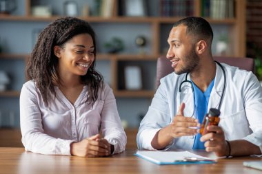 Happy millennial african american female patient feel satisfied pleased with good hospital medical service after consultation with middle eastern male doctor, therapist prescribing medication