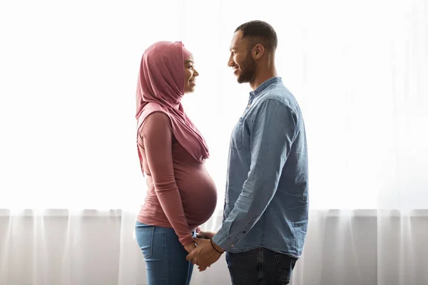 Married Pregnant Muslim Couple Standing Window Home Holding Hands Happy — Foto de Stock