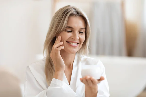 Positive Attractive Adult Blonde Woman Silky Bathrobe Using Luxury Facial — Zdjęcie stockowe