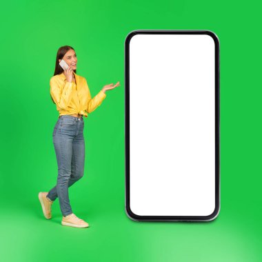Yeşil Stüdyo 'nun arka planında boş ekranlı, cep telefonuyla konuşan mutlu bayan. Mobil İletişim Konsepti. Kare çekim, Mockup