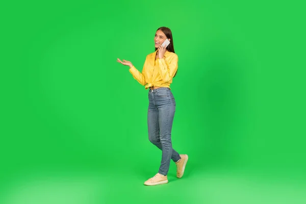 Millennial Woman Talking Mobil Walking Looking Aside Posing Green Background — Stock fotografie