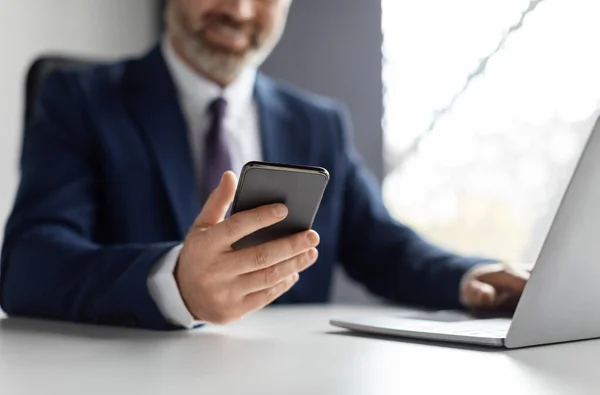 Smiling Mature Businessman Using Smartphone Working Laptop Modern Office Unrecognizable — Photo