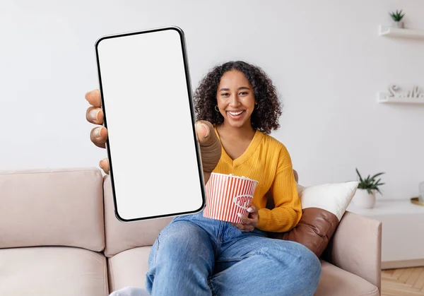 Cheerful Young Black Female Holding Popcorn Showing Big Blank Smartphone — Foto Stock