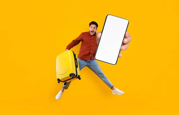 Excited Tourist Guy Jumping Luggage Showing Big Blank Smartphone Camera — Stockfoto