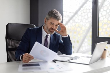 Busy Middle Aged Entrepreneur Working With Documents In Modern Office, Focused Businessman In Suit Sitting At Workplace And Reading Financial Papers, Checking Company Annual Report, Free Space