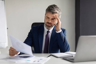 Stress At Work. Focused Mature Businessman Working With Papers In Office, Middle Aged Male Entrepreneur In Suit Reading Documents While Sitting At Desk, Suffering Business Problems, Closeup Shot