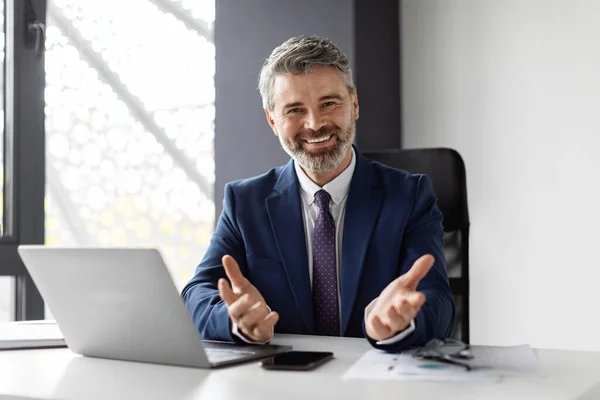 Successful Middle Aged Businessman Sitting Desk Office Smiling Gesturing Camera — Stok fotoğraf