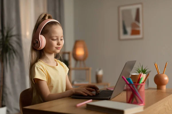 Schoolgirl Typing Laptop Learning Online Wearing Headphones Sitting Desk Home — Stock fotografie