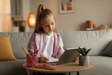 E-öğrenme. Liseli Kız, Tablet Öğrenme 'yi kullanıyor. İnternetten not alıyor. Evdeki koltukta oturuyor. Ödev yapan bir kız çocuğu. Modern İnternet Eğitimi Konsepti