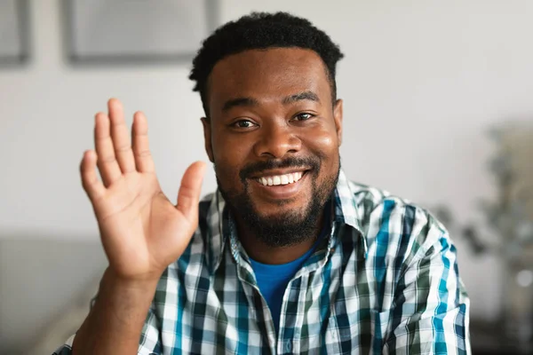 Cheerful African American Man Waving Hand Smiling To Camera Sitting Posing At Home. Millennial Guy Gesturing Hello Greeting. Video Call, Distance Communication Concept