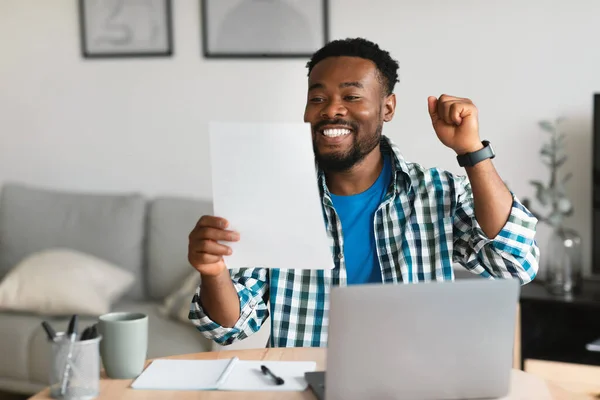 Joyful Black Guy Using Laptop Gesturing Yes Holding Paper Celebrating —  Fotos de Stock