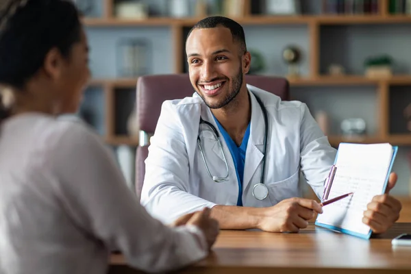 Cheerful Young Arabic General Practitioner Showing Black Lady Patient Treatment — Stock fotografie