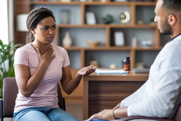 Sick Young Black Woman Touching Her Chest While Having Conversation — Stockfoto