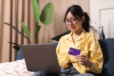 Japon Kadın İnternet üzerinden bilgisayar ve kredi kartı kullanarak alışveriş yapıyor ödemeyi evdeki koltukta oturan internet bankacılığı hizmeti üzerinden yapıyor. Ticaret Konsepti