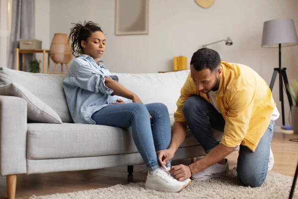 Black Husband Caring Pregnant Wife Lacing Her Shoes Sitting Couch — Φωτογραφία Αρχείου