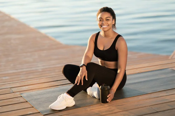 Attractive Athletic Millennial Black Woman Sitting Fitness Mat Drinking Protein — стоковое фото