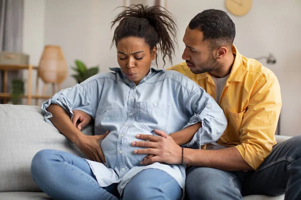 Ciężarna Afroamerykanka Cierpiąca Bóle Porodowe Mąż Przytulający Kanapie Domu Żona — Zdjęcie stockowe
