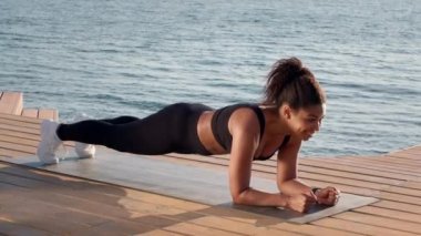 Açık havada spor eğitimi. Genç mutlu, zayıf Afrikalı Amerikalı sporcu. Göl kenarındaki iskelede egzersiz yapıyor. Egzersiz yapıyor.