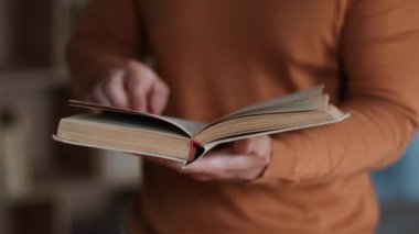 Read hobby. Close up shot of unrecognizable adult man turning page and keep reading interesting book, slow motion