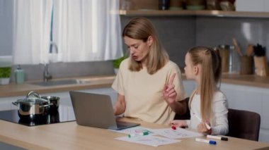 Stressful remote work. Busy mother freelancer typing on laptop at kitchen, her little daughter disturbing her, want some attention and feeling offended, tracking shot, slow motion, free space
