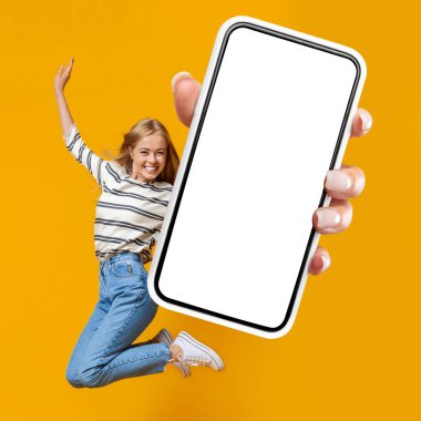 Happy young blonde woman jumping in the air on orange studio background, showing mobile phone with white blank screen, enjoying newest dating mobile application, chatting with guys, mockup, collage