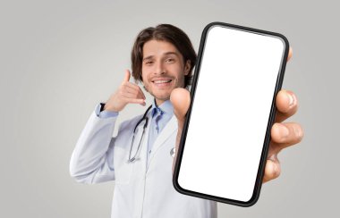 Positive medical specialist showing call gesture and smartphone with white blank screen for advertisement over white studio background, empty space, mockup, collage for e-healthcare