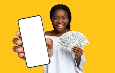 Başarıyı kutlayan neşeli siyahi bayan, beyaz ekranlı ve dolarlı akıllı telefonu gösteriyor, bir sürü banknot tutuyor ve heyecanla haykırıyor, kumar mobil uygulaması kullanıyor, taklit ediyor, kolaj yapıyor.