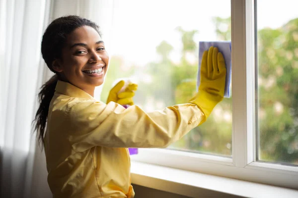 Happy Black Woman Cleaning Window Glass Holding Rag Detergent Spray — Foto Stock