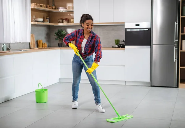 Cheerful Millennial Black Female Housewife Rubber Gloves Mop Washes Floor — 스톡 사진