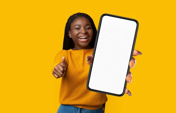 Positive Young Black Woman Showing Smartphone Empty Screen Gesturing Thumb — 图库照片