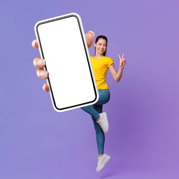 Cheerful Pretty Asian Millennial Lady Jumping Air Showing Smartphone Blank — Foto Stock