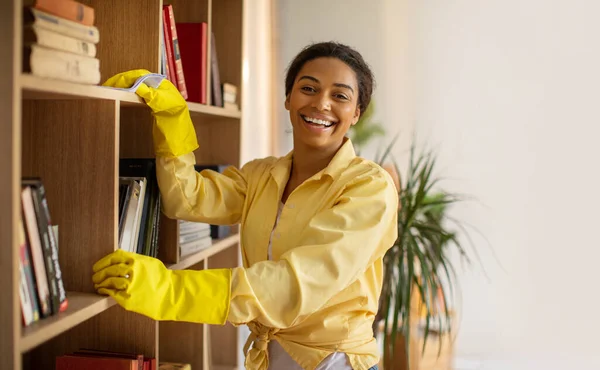 Happy African American Woman Dusting Cleaning Bookshelf Rag Smiling Camera — ストック写真