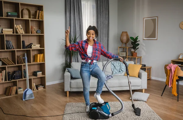 Cheerful Glad Millennial Black Housewife Vacuuming Vacuum Cleaner Pointing Finger — ストック写真
