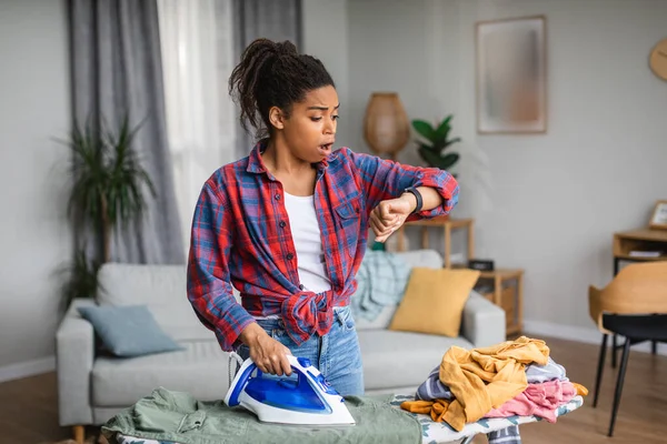 Shocked Millennial African American Woman Housewife Ironing Clothes Looks Clock — Fotografia de Stock