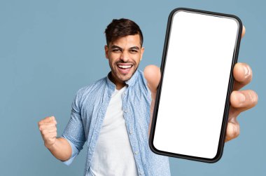 Mutlu, genç, orta doğulu, sımsıkı titreyen yumruğunu sallayan ve beyaz ekranlı akıllı telefonu gösteren, zaferini kutlayan, hisse senedi ve pazarlardan online ticaret yapan, kolaj, model