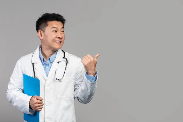 Usmívající Dospělý Asijský Lékař Bílém Kabátě Stetoskopem Tabletem Ukazující Prstem — Stock fotografie