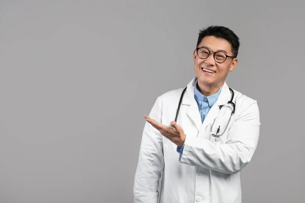 Uśmiechnięty Koreański Terapeuta Białym Płaszczu Okulary Stetoskopem Pokazują Dłoń Pustej — Zdjęcie stockowe