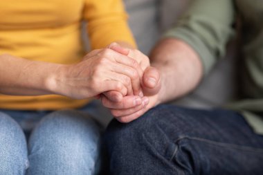 Support In Marriage. Closeup Shot Of Man And Woman Holding Hands Together, Unrecognizable Wife And Husband Sitting On Couch And Crossing Fingers, Expressing Empathy And Love To Each Other, Cropped