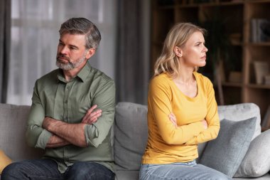 Crisis In Relations. Middle Aged Husband And Wife Offending To Each Other After Argue, Grumpy Spouses Sitting On Couch With Folded Arms, Married Couple Angry After Domestic Quarrel, Free Space