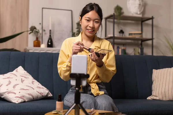Beauty Blog. Asian Female Blogger Making Makeup Filming On Cellphone Sitting On Sofa At Home. Woman Advertising Cosmetics Products. Professional Blogging Concept. Selective Focus