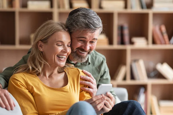 Happy Middle Aged Couple Watching Family Photos Smartphone Home Cheerful — Stok fotoğraf