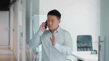 Business problems solution. Confident asian mature businessman talking with partners or colleagues via cellphone, resolving troubles at office, slow motion