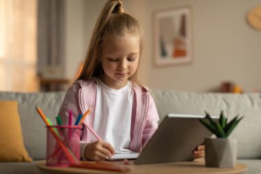 E-öğrenme. Liseli kız dijital tablet kullanıyor ödevlerini internette yapıyor ve evdeki kanepeye oturmuş not alıyor. Liseli Kız Uzaktan Öğrenme Yazıyor. Modern Eğitim Konsepti